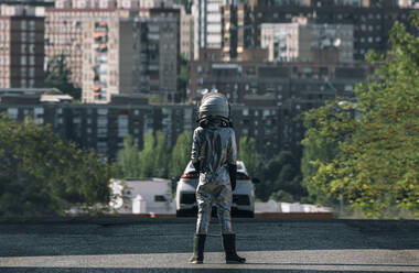 Rückansicht eines als Astronaut verkleideten Jungen, der auf einer Straße in der Stadt steht - JCMF00218