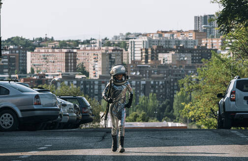Boy dressed as an astronaut walking on a street in the city - JCMF00219