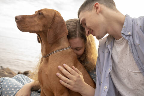 Young couple with dog at the beach stock photo