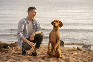 Junger Mann mit seinem Hund am Strand beim Training - VPIF01525