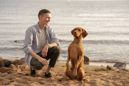 Young man with his dog at the beach during training - VPIF01525