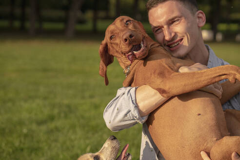 Young man with his dog, cuddling on a meadow - VPIF01529