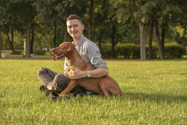 junger Mann mit seinem Hund auf einer Wiese - VPIF01532