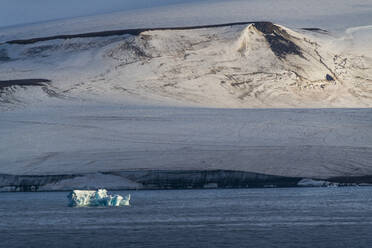 Eisberg, der vor einem flachen, mit Eis bedeckten Tafelberg schwimmt, Archipel Franz Josef Land, Gebiet Archangelsk, Arktis, Russland, Europa - RHPLF11217