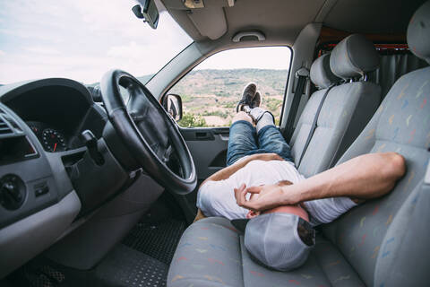 Junger Mann mit Beinprothese ruht sich im Wohnmobil aus, lizenzfreies Stockfoto