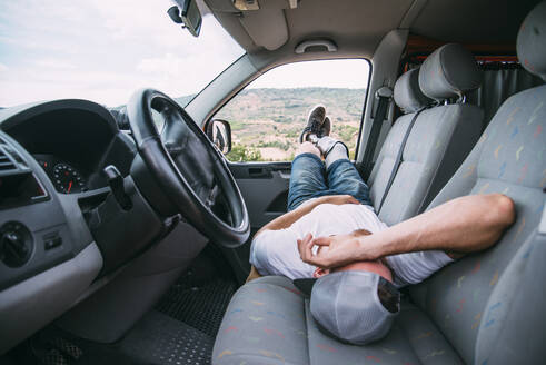 Junger Mann mit Beinprothese ruht sich im Wohnmobil aus - CJMF00011