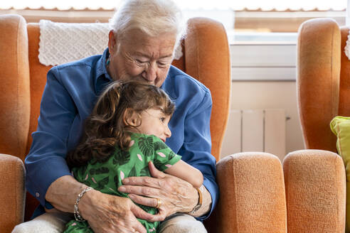 Großmutter, die ihre Enkelin im Wohnzimmer umarmt - GEMF03150