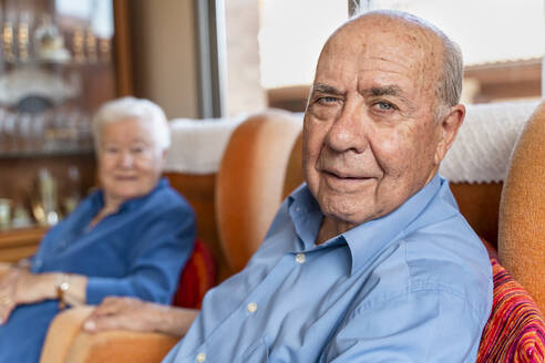Älterer Mann mit seiner Frau in einem Sessel im Wohnzimmer sitzend - GEMF03160