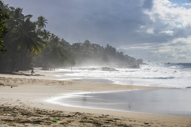 Landschaftliche Ansicht von Wellen, die am Ufer gegen den bewölkten Himmel in Trinidad und Tobago plätschern, Karibik - RUNF03190