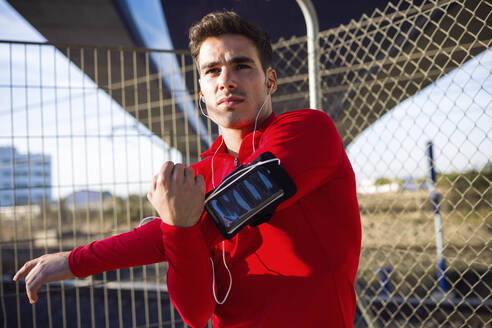 Jogger mit Smartphone in der Armtasche, der seinen Arm ausstreckt - JSRF00572