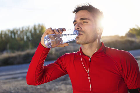 Junge Joggerin trinkt aus einer Wasserflasche, lizenzfreies Stockfoto