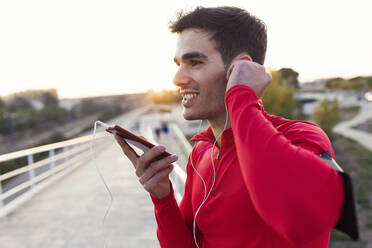 Jogger mit Smartphone in der Armtasche, der sich mit seinem Smartphone unterhält - JSRF00599