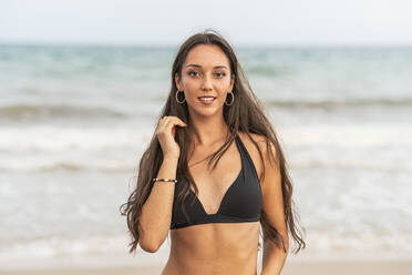 Portrait of attractive young woman in black bikini walking on