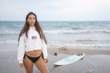 Porträt einer jungen Frau mit Surfbrett am Strand - DLTSF00149