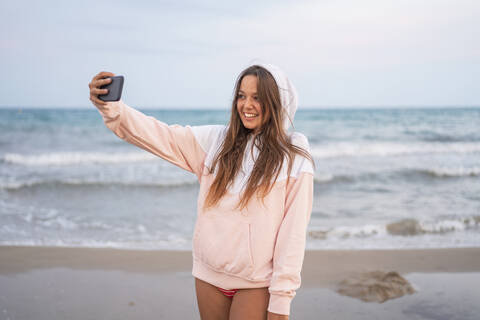 Happy young woman taking a selfie on the beach stock photo