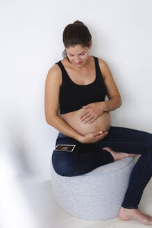 Junge schwangere Frau mit Ultraschallbild ihres ungeborenen Babys - HMEF00581