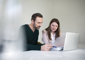 Geschäftsmann und Angestellter mit Laptop und Dokumenten bei der Arbeit am Schreibtisch im Büro - MIKF00035