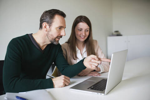 Geschäftsmann und Angestellter mit Laptop am Schreibtisch im Büro, lizenzfreies Stockfoto