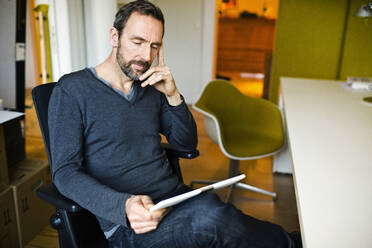 Businessman using tablet at desk in office - MIK00049