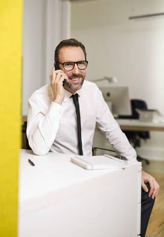 Geschäftsmann telefoniert am Schreibtisch im Büro, lizenzfreies Stockfoto