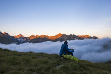 Ein Wanderer beobachtet den Sonnenuntergang in den Pyrenäen und eine Wolkeninversion in der Nähe der Schutzhütte Pombie entlang des Wanderwegs GR10, Pyrenees Atlantiques, Frankreich, Europa - RHPLF11972