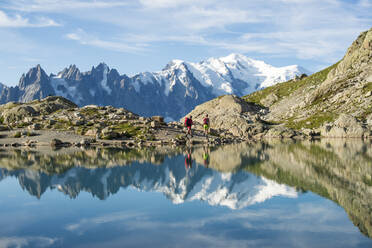 Wanderer und der Gipfel des Mont Blanc, der sich im Lac Blanc spiegelt, auf der Trekkingroute Tour du Mont Blanc in den französischen Alpen, Haute Savoie, Auvergne-Rhone-Alpes, Frankreich, Europa - RHPLF11974