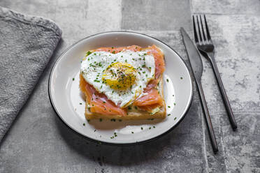 High angle view of toasted bread with salmon and heart shaped fried egg in plate on table - SARF04344