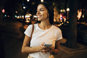 Young woman using smartphone in the city at night - OYF00064