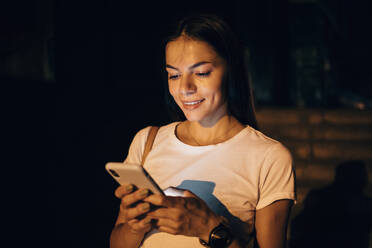 Young woman using smartphone in the city at night - OYF00070