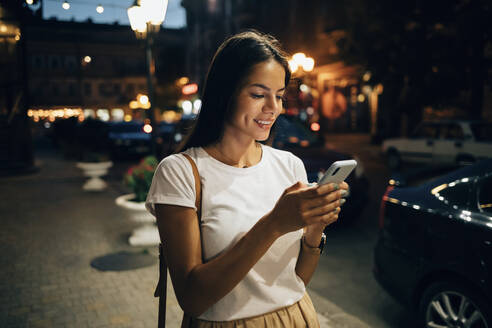 Young woman using smartphone in the city at night - OYF00071