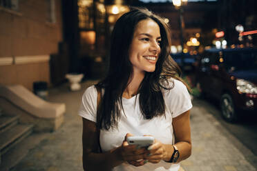 Young woman using smartphone in the city at night - OYF00072