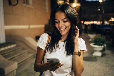 Young woman using smartphone in the city at night - OYF00073