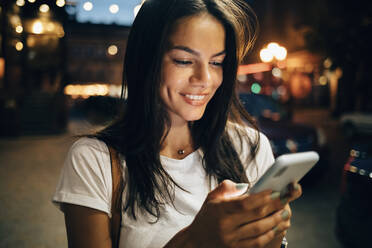 Young woman using smartphone in the city at night - OYF00076