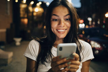 Young woman using smartphone in the city at night - OYF00079