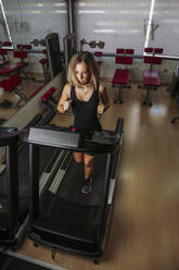 Junge Frau trainiert auf einem Laufband in einem Fitnessstudio - LJF01003