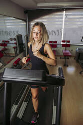 Young woman training on a treadmill in a gym - LJF01004