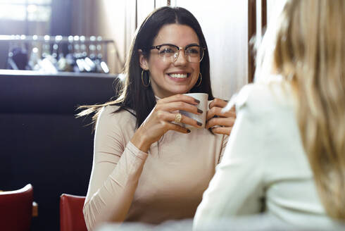 Portrait of a smiling woman with friend in a cafe - JSRF00607