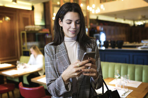 Geschäftsfrau benutzt Mobiltelefon in einem Restaurant, lizenzfreies Stockfoto