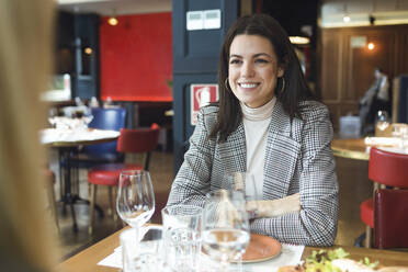 Porträt einer lächelnden Geschäftsfrau, die an einem Tisch in einem Restaurant sitzt - JSRF00621