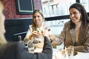 Smiling businesswomen meeting and clinking wine glasses in a restaurant - JSRF00625