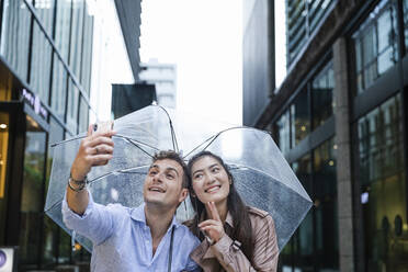 Glückliches Paar mit Regenschirm macht ein Selfie in Ginza, Tokio, Japan - MCVF00026