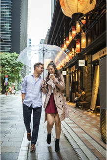 Glückliches Paar mit Regenschirm beim Spaziergang in Ginza, Tokio, Japan - MCVF00032