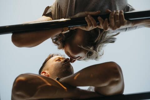 Junges Paar, das sich auf einem Klettergerüst küsst, lizenzfreies Stockfoto