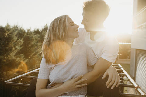 Junges Paar, das sich bei Sonnenuntergang auf einem Klettergerüst küsst, lizenzfreies Stockfoto