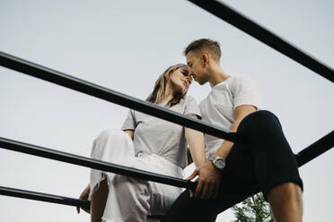 Junges Paar, das sich auf einem Klettergerüst küsst - LHPF00875