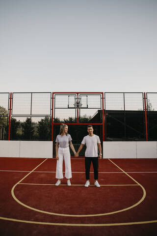 Junges Paar auf einem Basketballplatz, Hände haltend, lizenzfreies Stockfoto