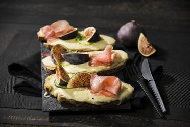 High angle view of baked cheese bread with fig and ham served on table - MAEF12944