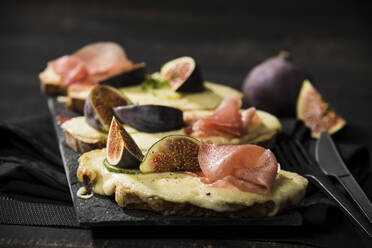Close-up of baked cheese bread with fig and ham served on table - MAEF12946
