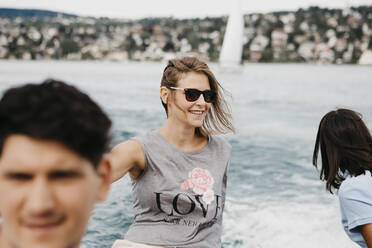 Glückliche Frau mit Freunden bei einem Bootsausflug auf einem See - LHPF00885