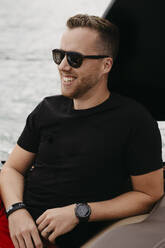 Glücklicher Mann mit Sonnenbrille bei einer Bootsfahrt auf einem See - LHPF00887